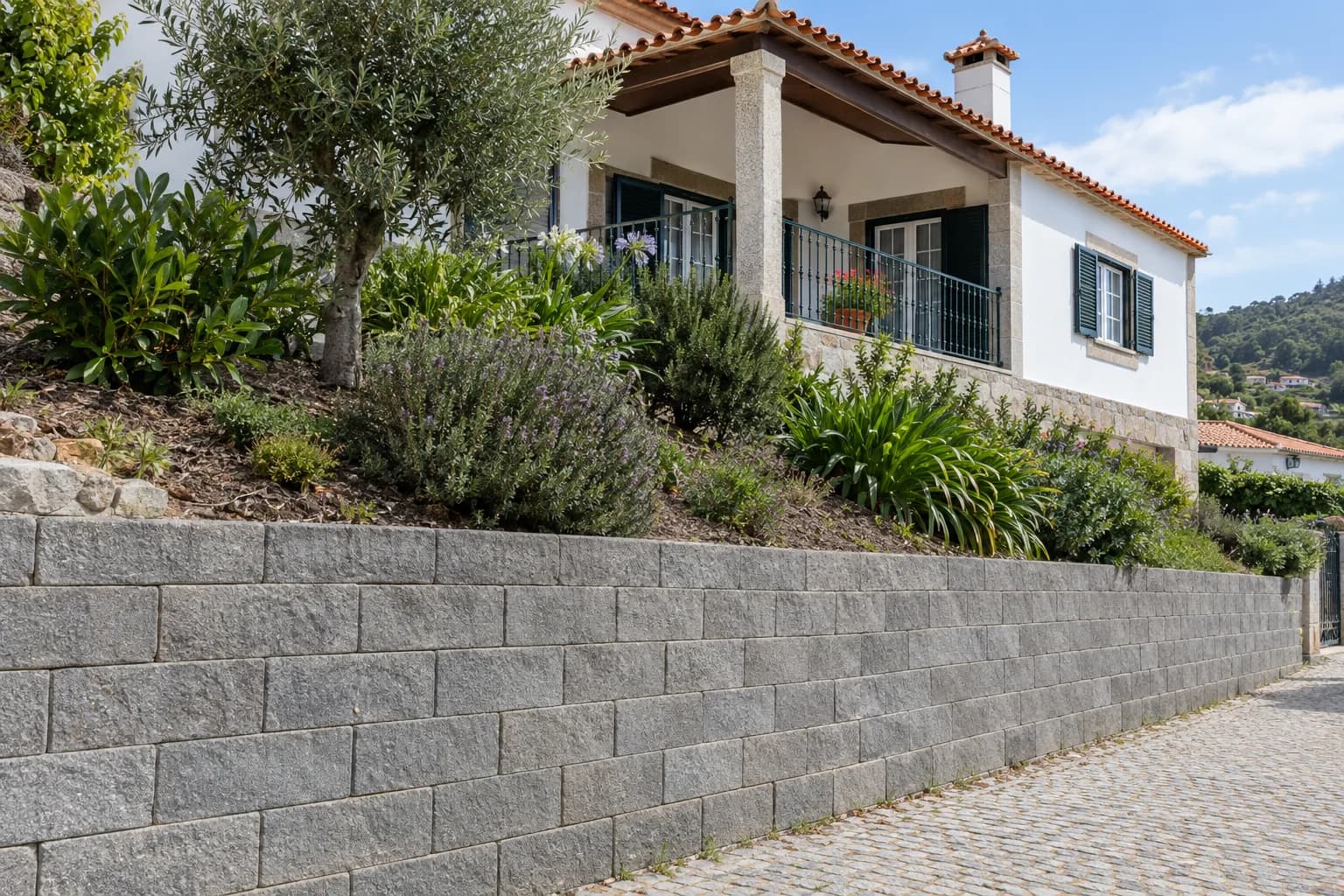 Muro de suporte de blocos de betão junto a um jardim em declive